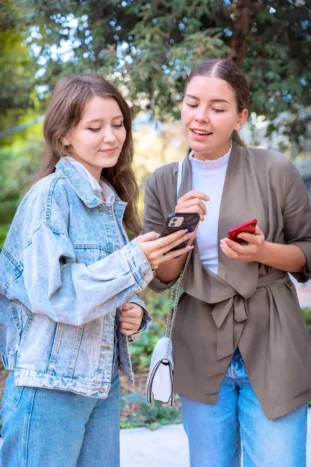 Two women looking at an app on their smartphone.